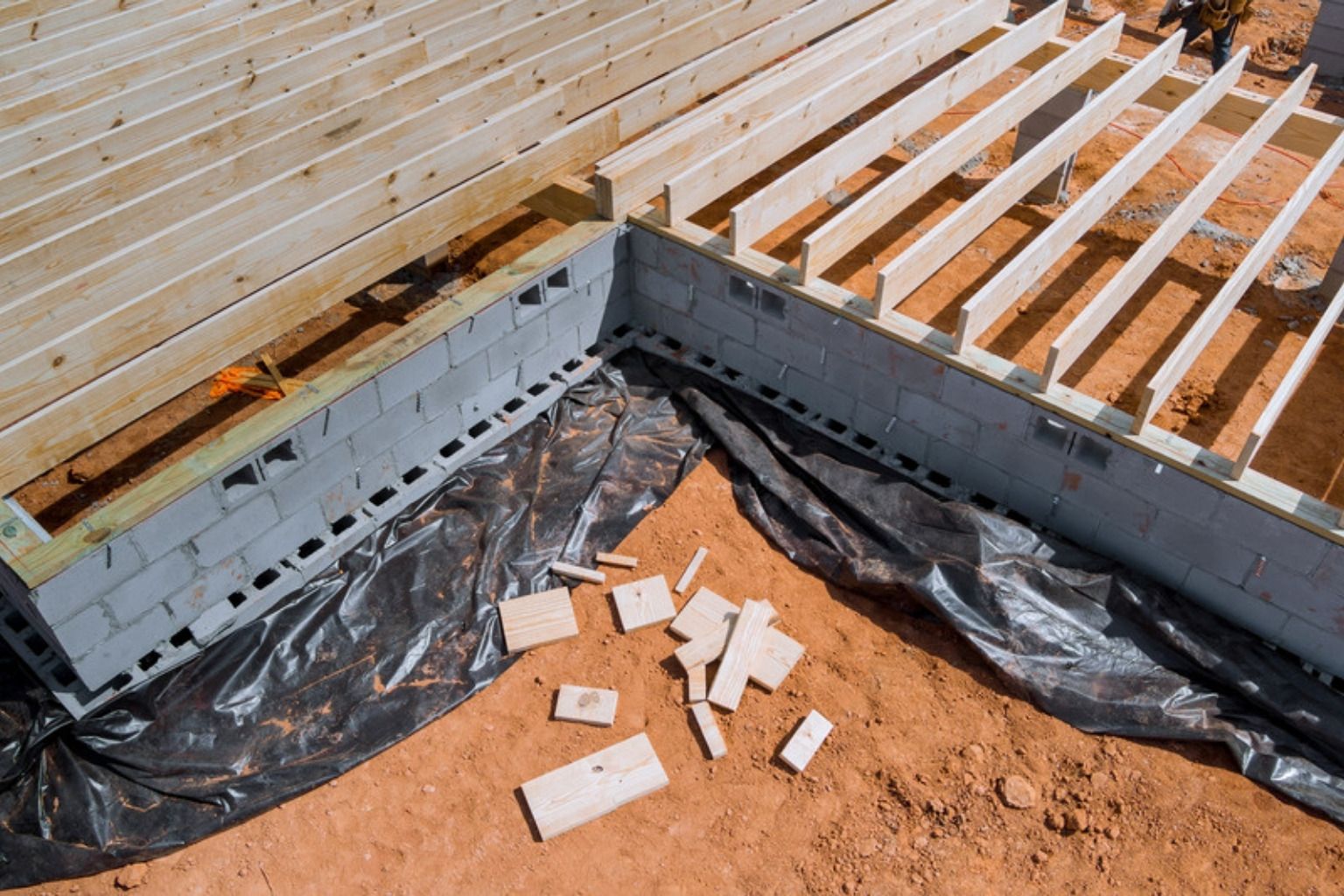 Hjørne af en ny terrasses underkonstruktion med strøer på betonfundament og fiberdug
